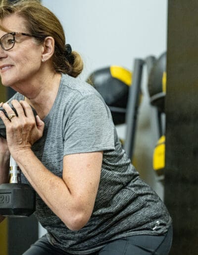 Woman exercising with a dumbbell in a fitness training environment, showcasing strength training and personal fitness progress.