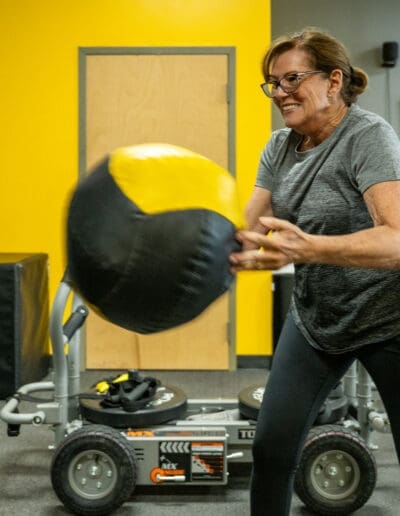 Woman exercising with a medicine ball in a fitness studio, showcasing strength training and conditioning.
