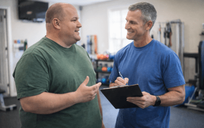 Personal trainer discussing fitness goals with client in a gym setting, emphasizing personalized training and motivation.